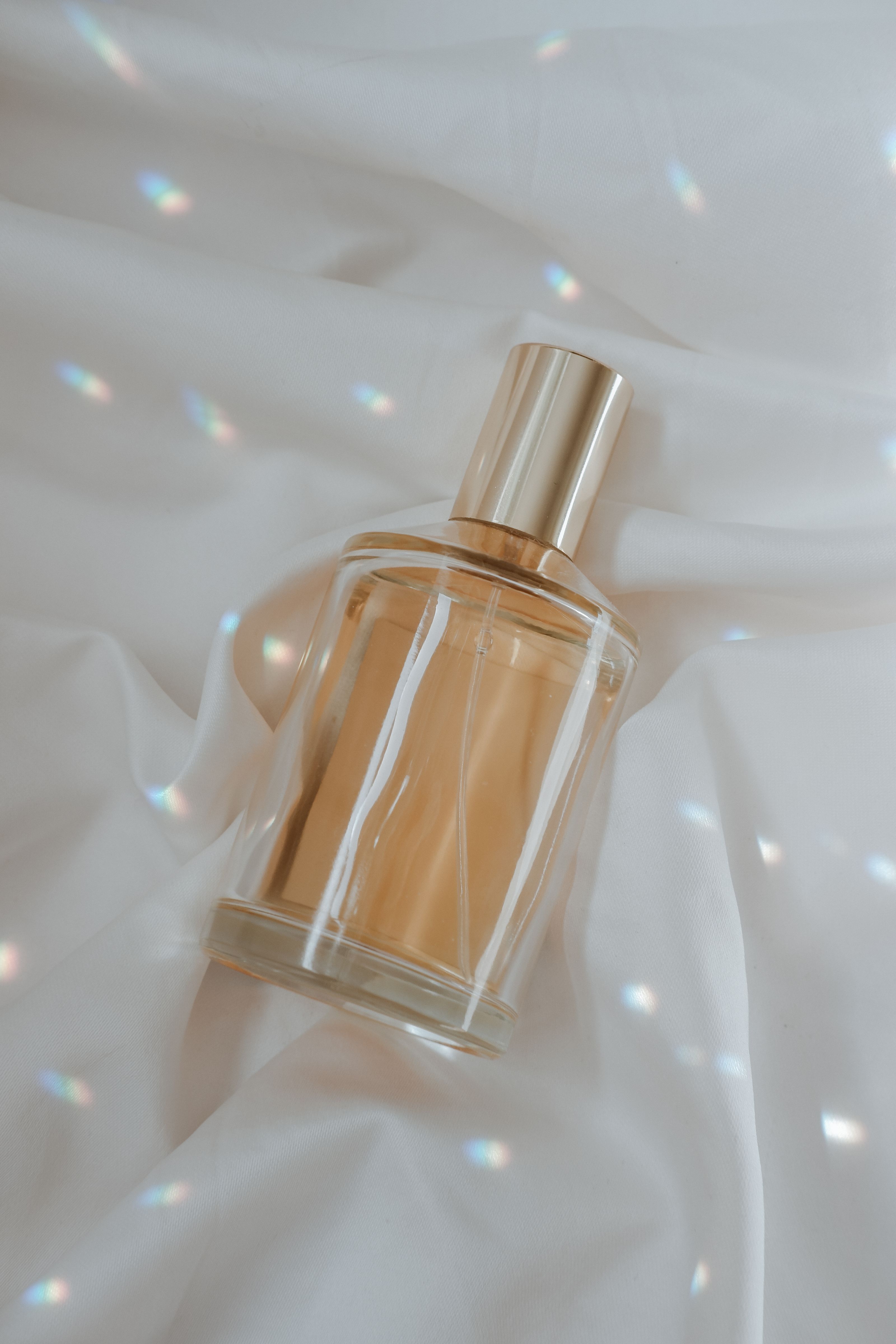 Um frasco de perfume luxuoso elegantemente exibido sobre um tecido de seda suave com reflexos de luz suave.
