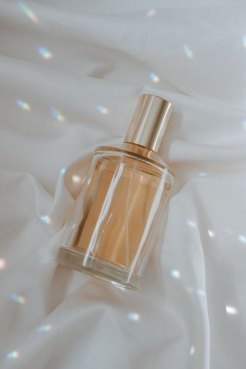 Free A luxurious perfume bottle elegantly displayed on soft satin fabric with soft light reflections. Stock Photo