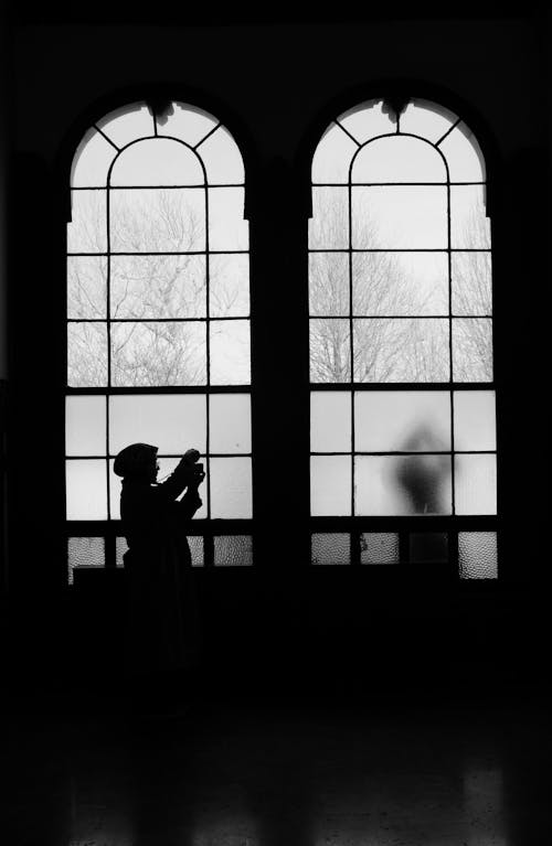 Woman in Hijab Standing in Darkness near Windows