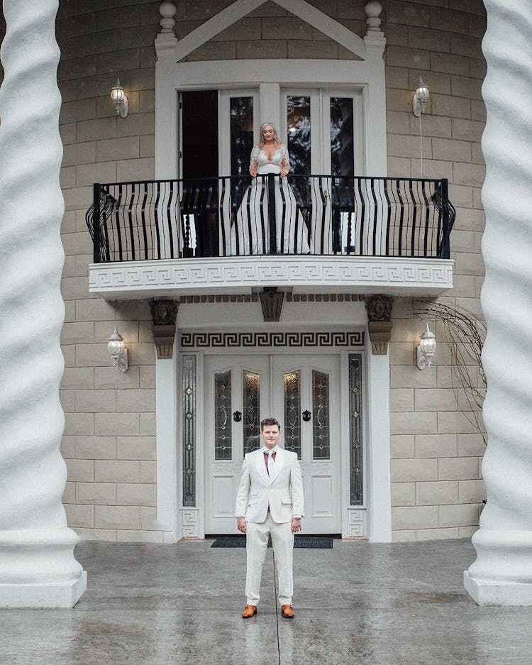 Elegant Groom Standing Against House And Waiting For Bride