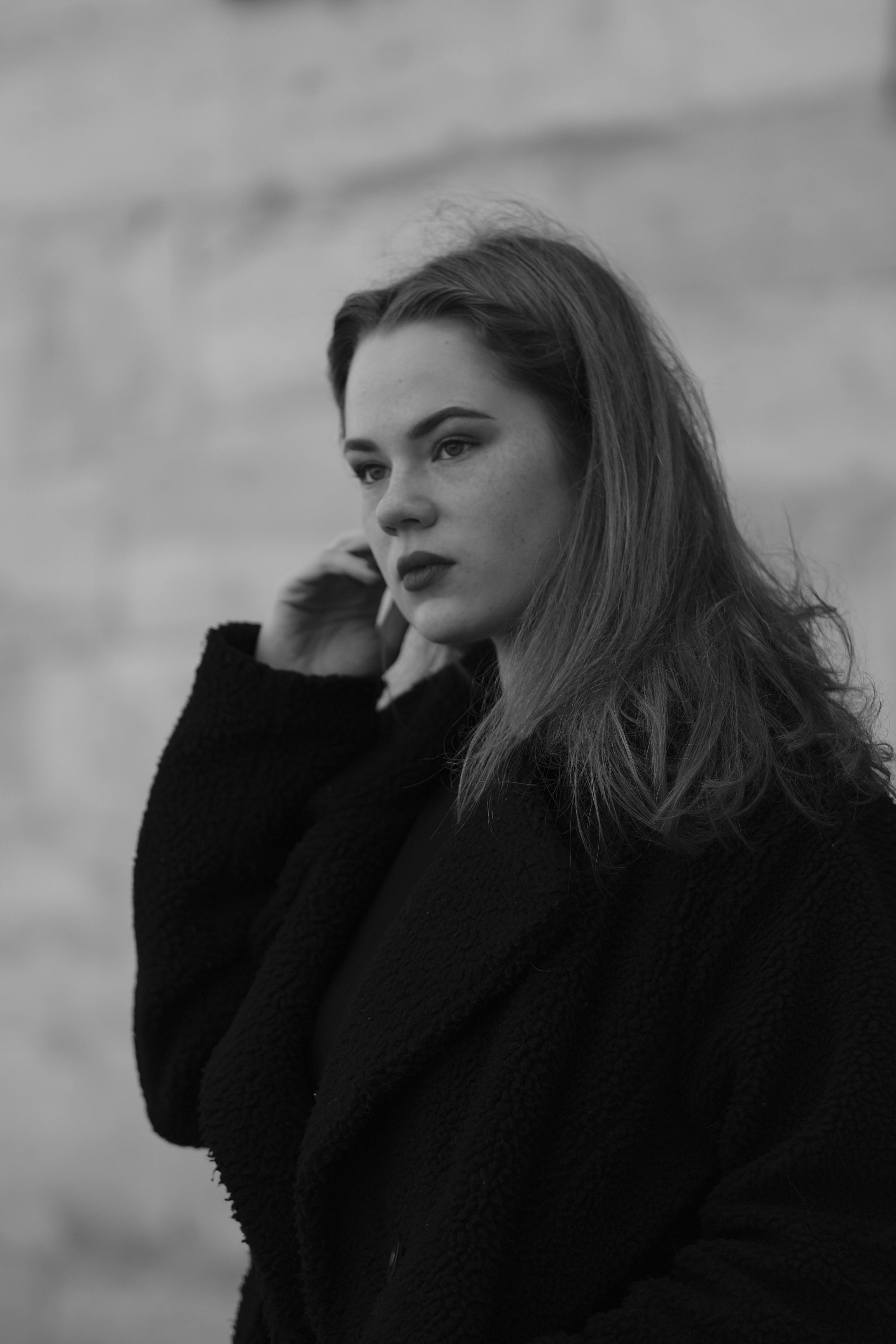 Stylish black and white portrait of a woman in a coat, exuding elegance and poise.