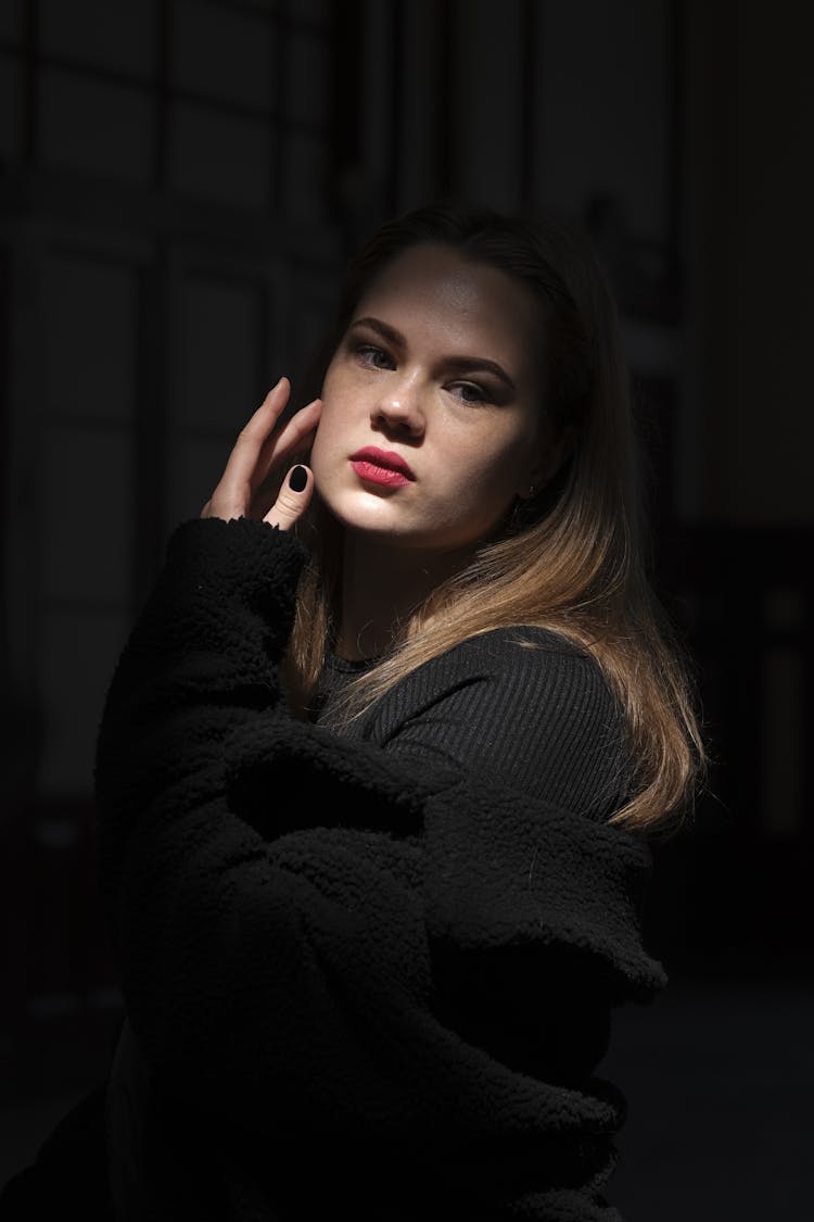 Young Woman In A Black Outfit Posing In A Dark Room 