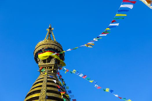 Explore the vibrant Swayambhunath Stupa in Kathmandu with colorful prayer flags fluttering under a clear blue sky.