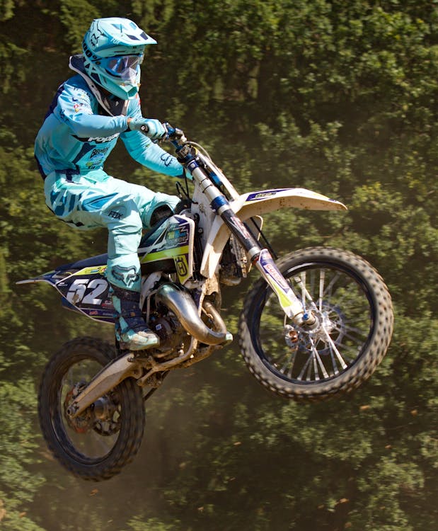 Man in Blue Mtx Suit Riding Blue and Yellow Dirt Motorcycle in Air