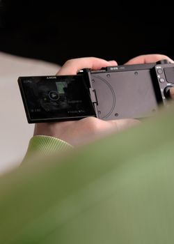 Close-up view of a person holding a digital camera displaying footage.