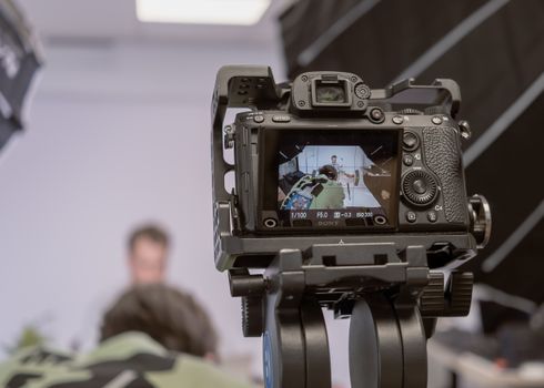 Close-up of a camera on a tripod capturing a portrait in a studio setting.