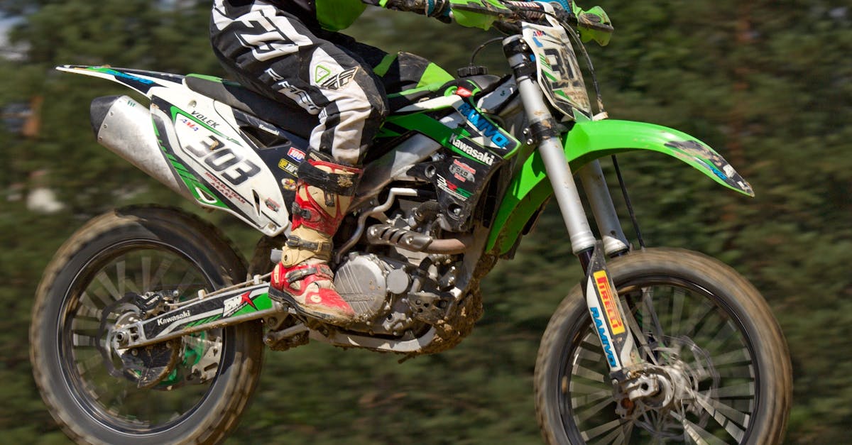 Man in Green White and Black Mtx Suit on Green and White 303 Dirt Motorcycle in the Air
