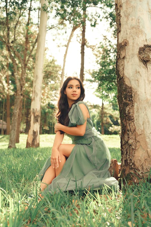 Photo of a Beautiful Young Woman in a Dress Sitting in the Forest