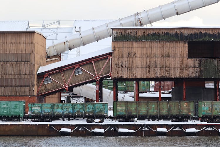 Pipe And Building Over Train Cars By River