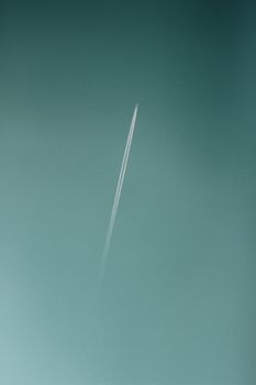 An airplane soars through a clear sky, leaving behind a distinct contrail.