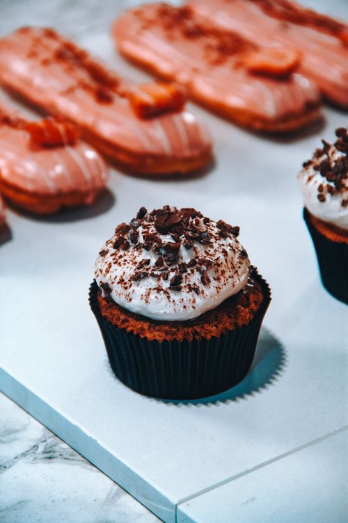 Free Delectable chocolate cupcake and eclairs on a sleek marble surface, perfect for dessert lovers. Stock Photo