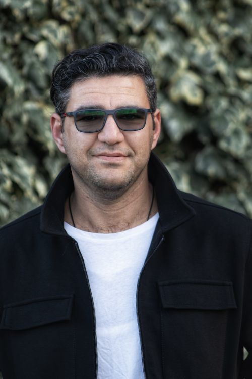 Free Casual portrait of a smiling man in sunglasses and jacket with an outdoor leafy background. Stock Photo