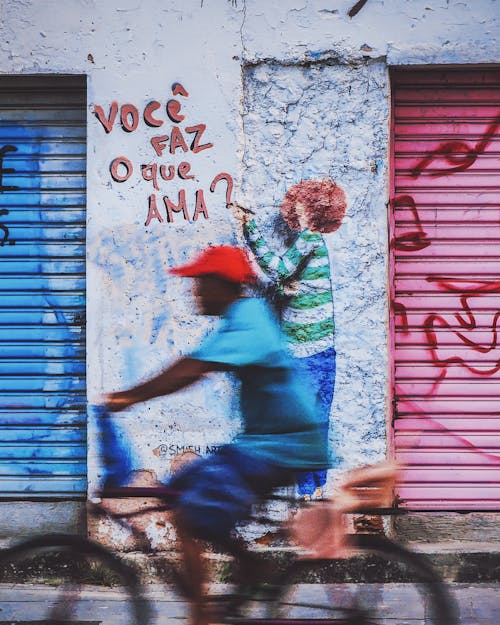 Man Riding a Bike by a Graffiti on the Wall