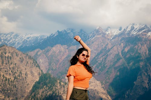 Brunette Woman Standing with Arm Raised in Mountains