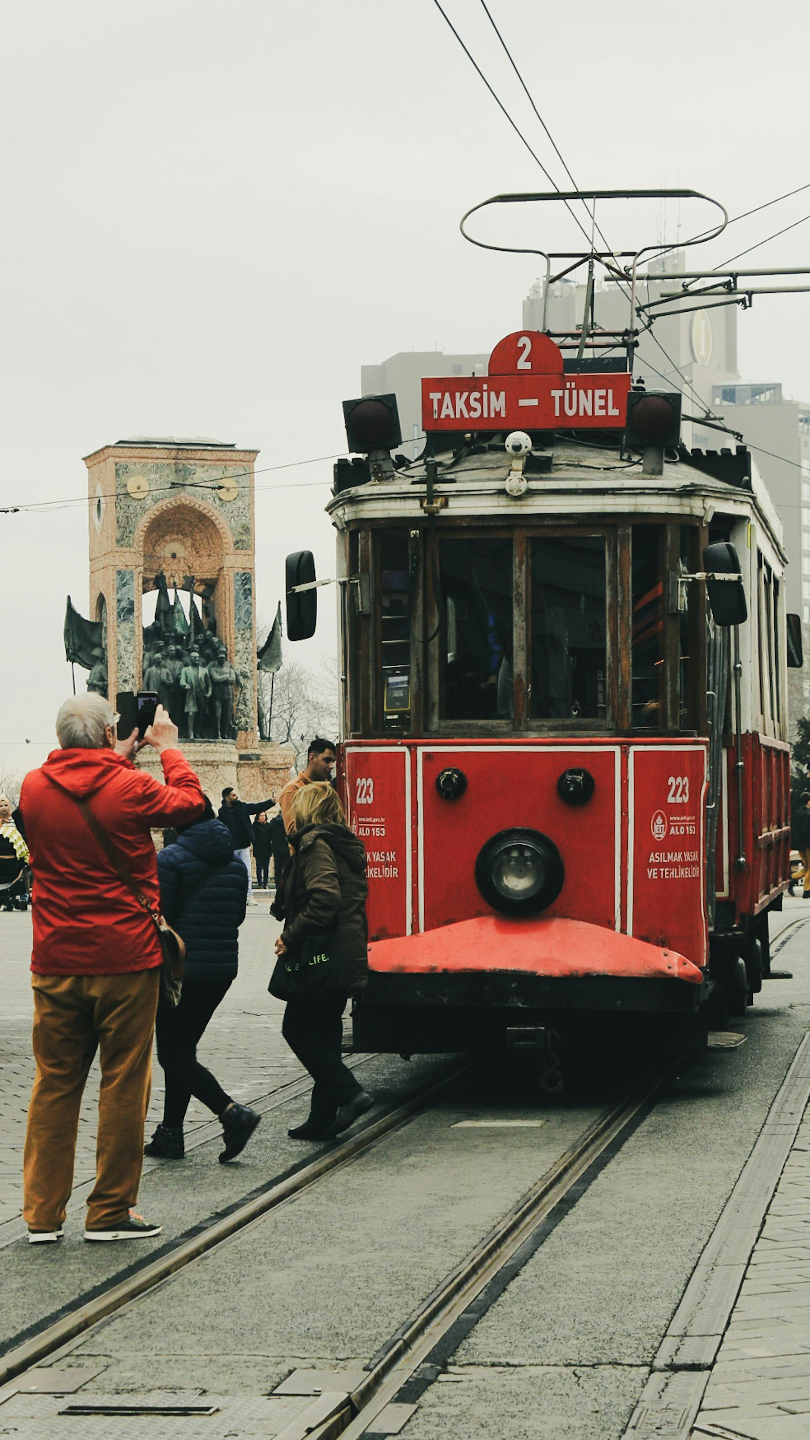 Historic red tram at Taksim Square in Istanbul, capturing urban life and classic transportation.