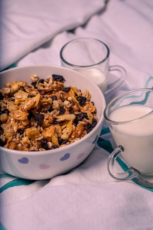 Free Bowl of Muesli and Glasses of Milk on a Bed Stock Photo