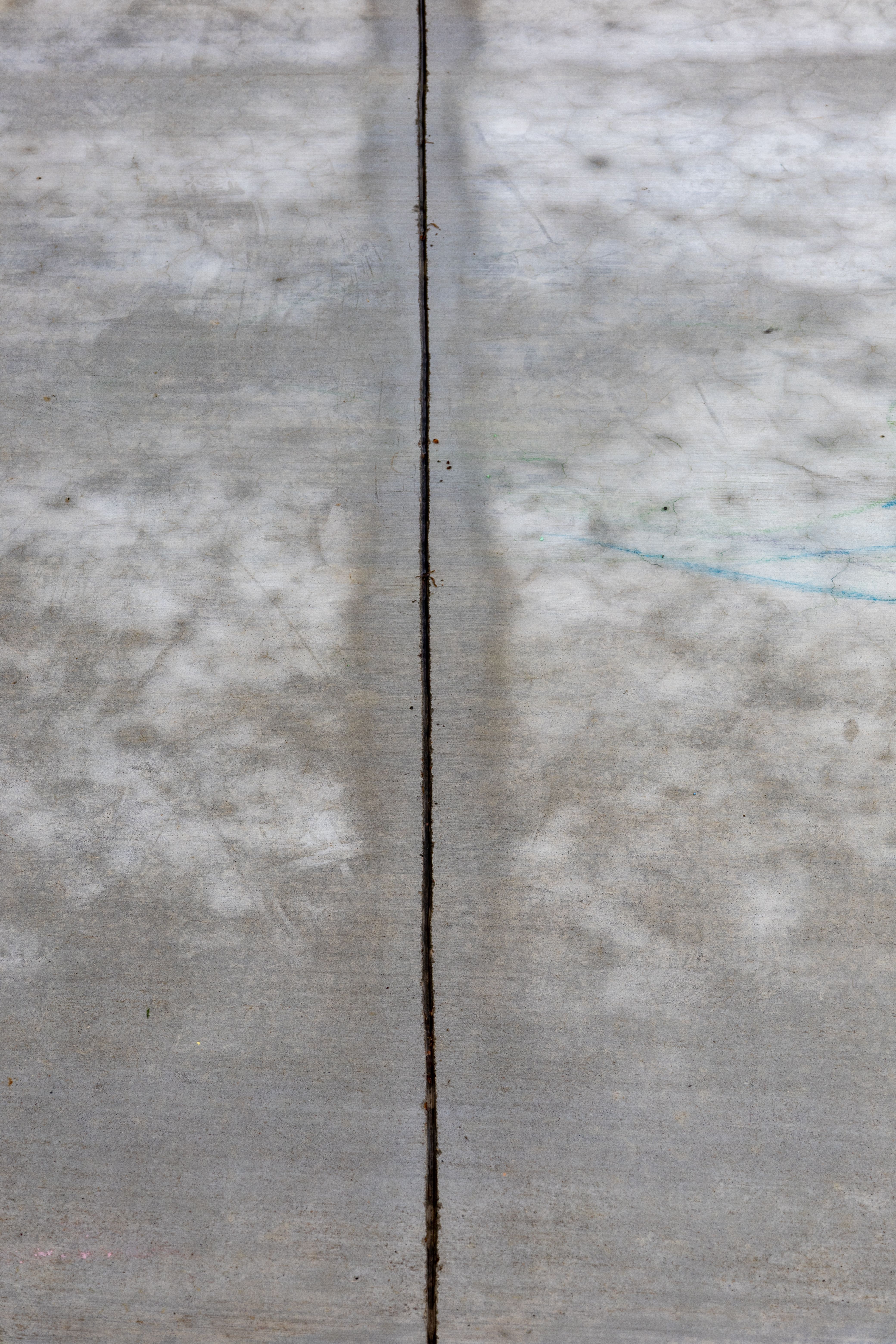 Detailed view of a cracked concrete surface, emphasizing texture and line.