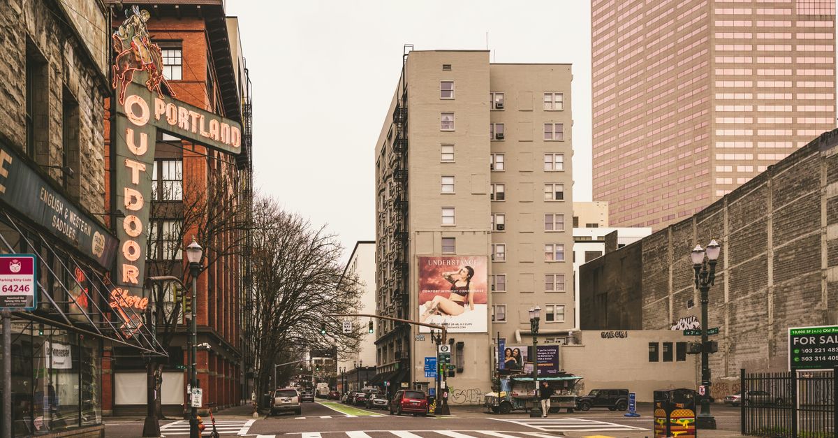 Urban street scene in downtown Portland featuring historic neon sign and modern architecture.