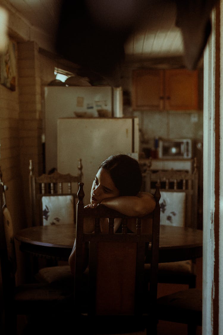 Troubled Woman Sitting In Kitchen