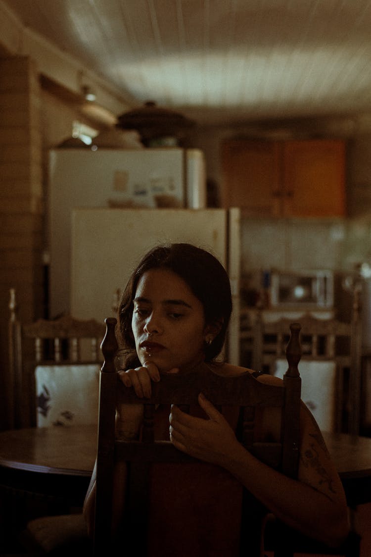 Pensive Woman Sitting In Kitchen