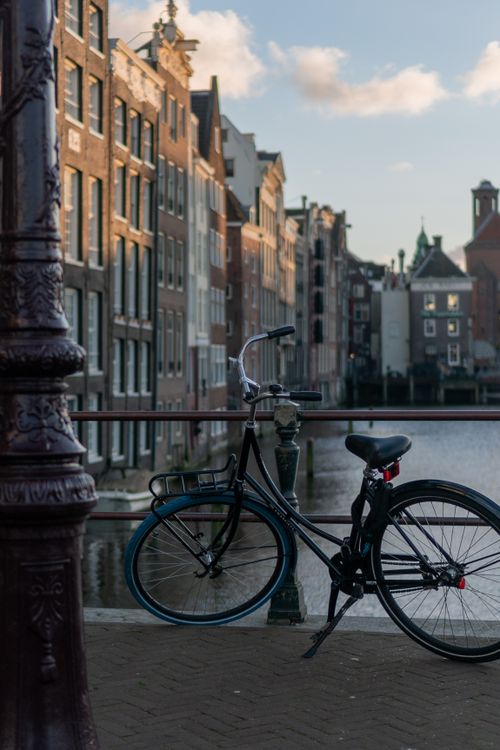 Free A scenic view of a bicycle on an Amsterdam canal bridge at dusk, highlighting urban architecture. Stock Photo