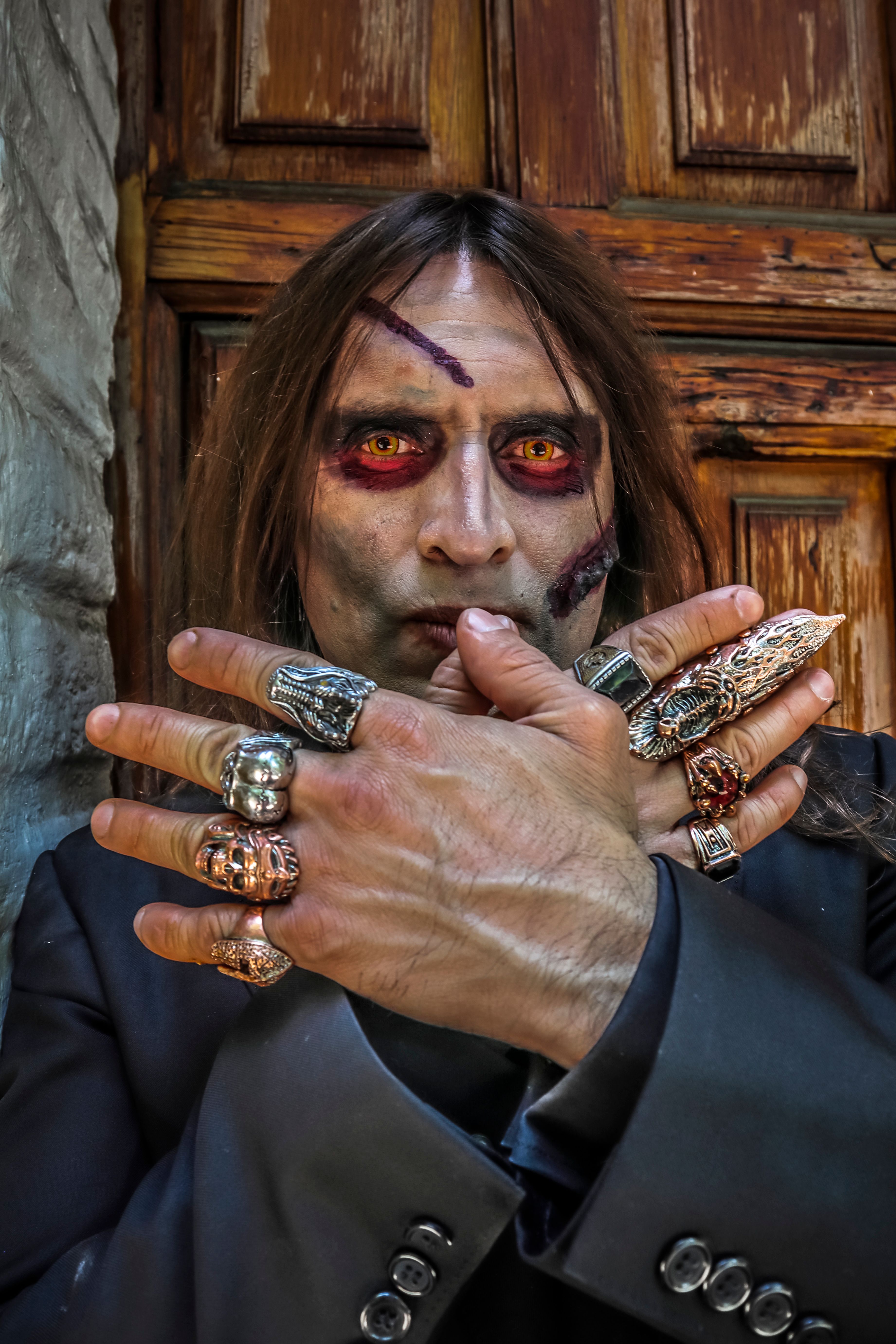 Dramatic portrait of a man with Halloween face paint and ornate rings.
