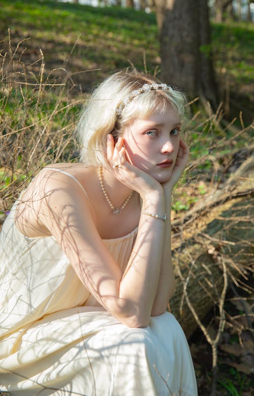 Portrait of a Pretty Blonde Wearing a White Dress Sitting Outdoors