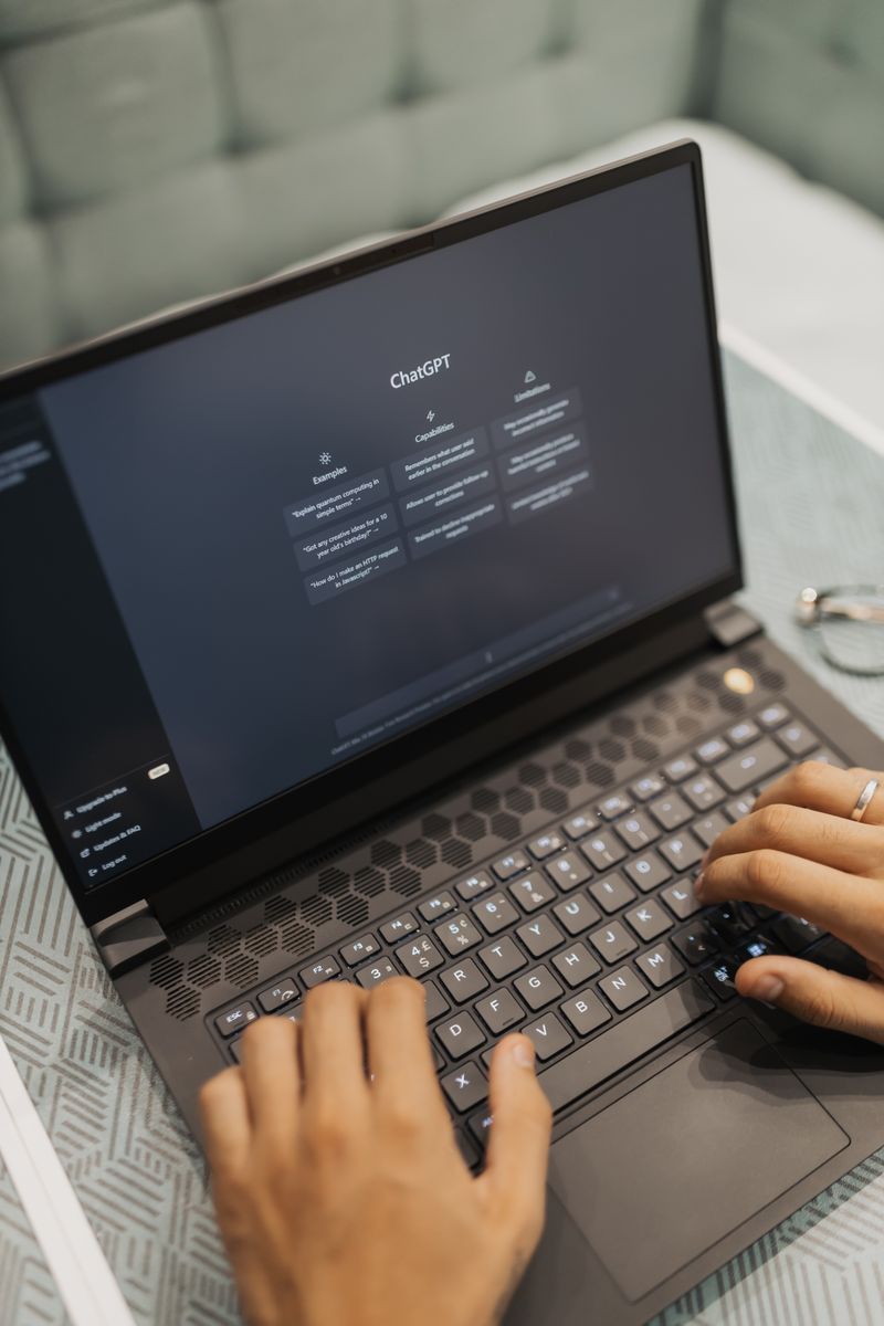 Close-up of hands typing on a laptop with AI software on the screen