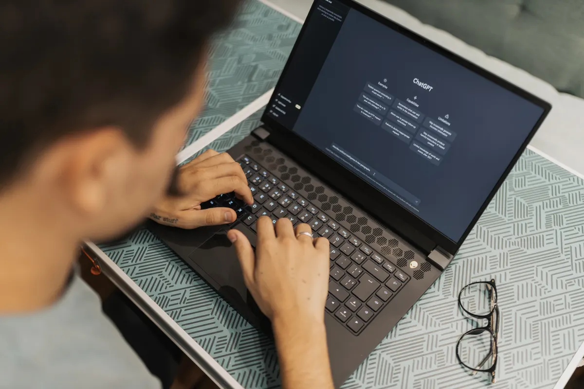 A person working on a laptop with an AI chat assistant open on screen, the kind of place buyers now ask for a recommendation instead of searching Google