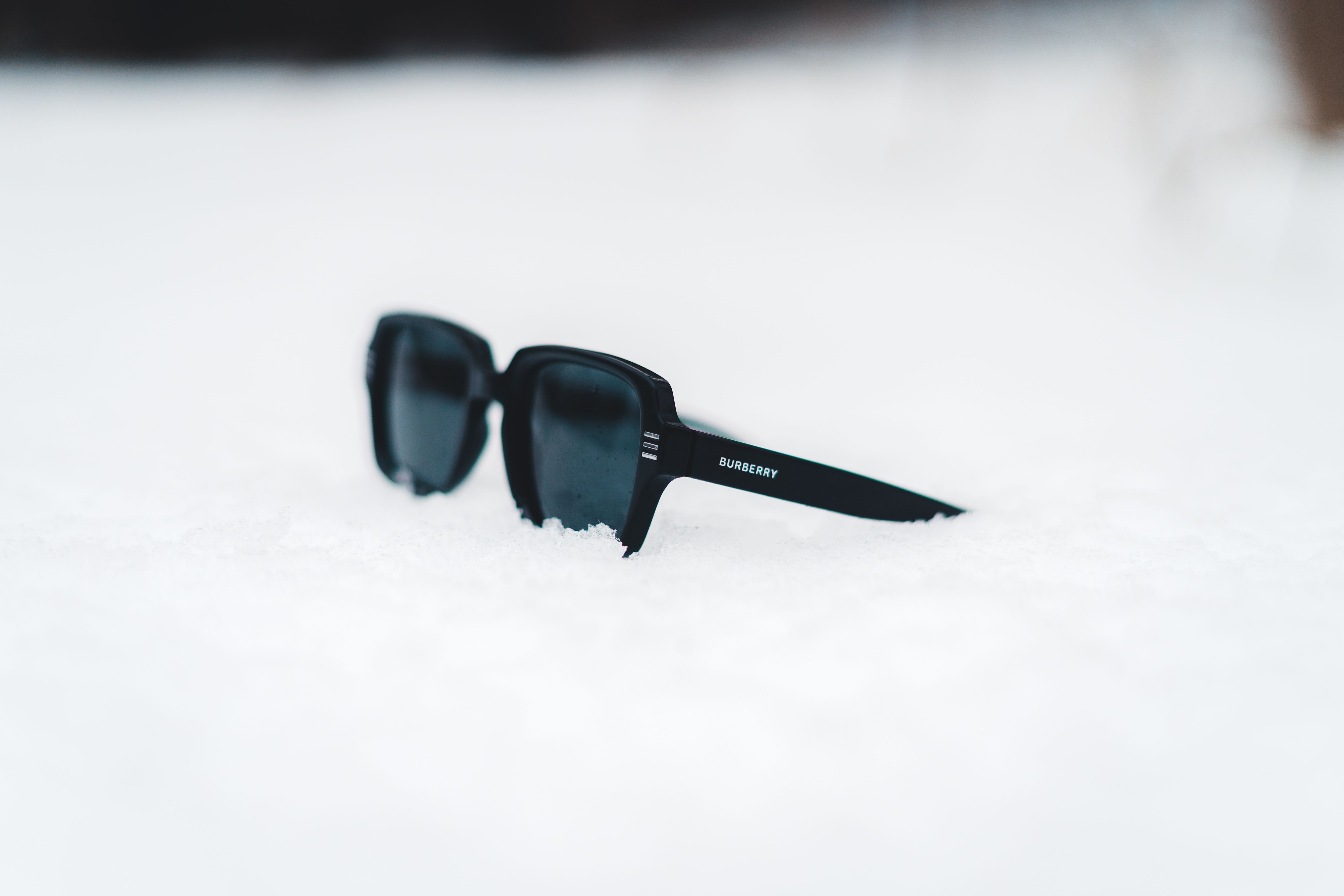 Stylish sunglasses rest on fresh snow, capturing a serene winter ambiance.