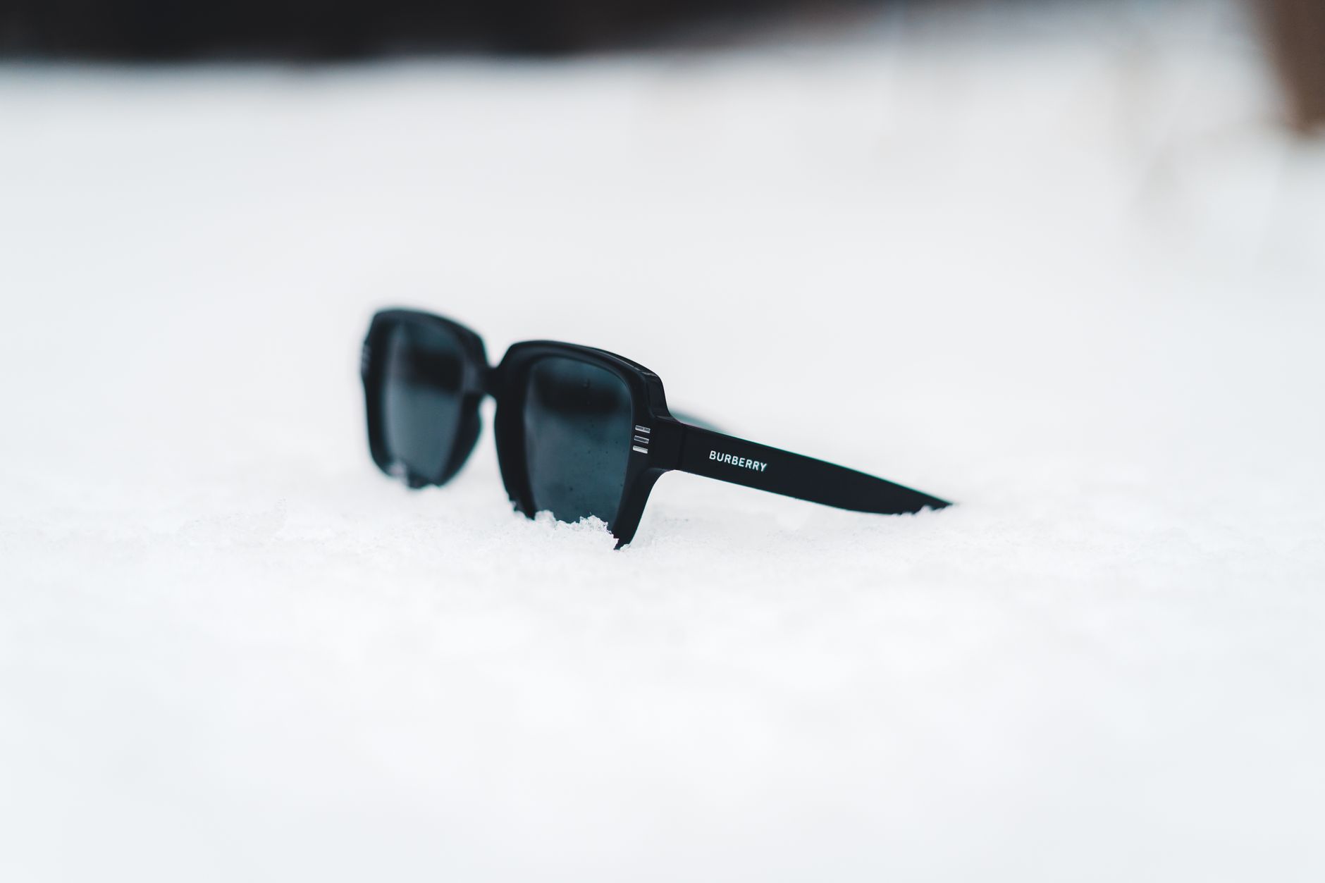 Stylish sunglasses rest on fresh snow, capturing a serene winter ambiance.