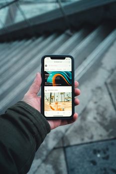 A person holds a smartphone displaying an app on a city staircase.