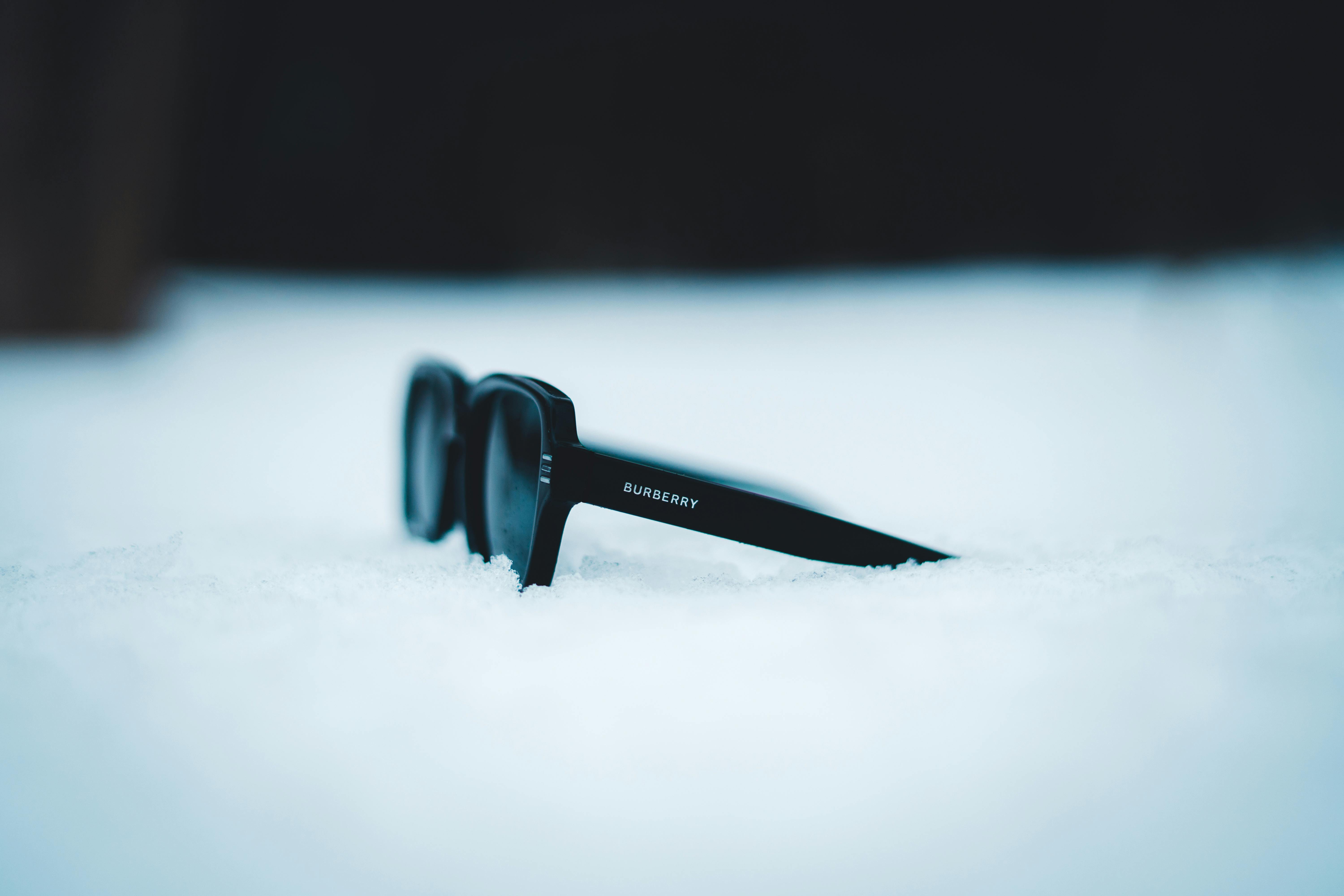 Free Close-up of sunglasses in snow, highlighting contrast and winter theme. Stock Photo