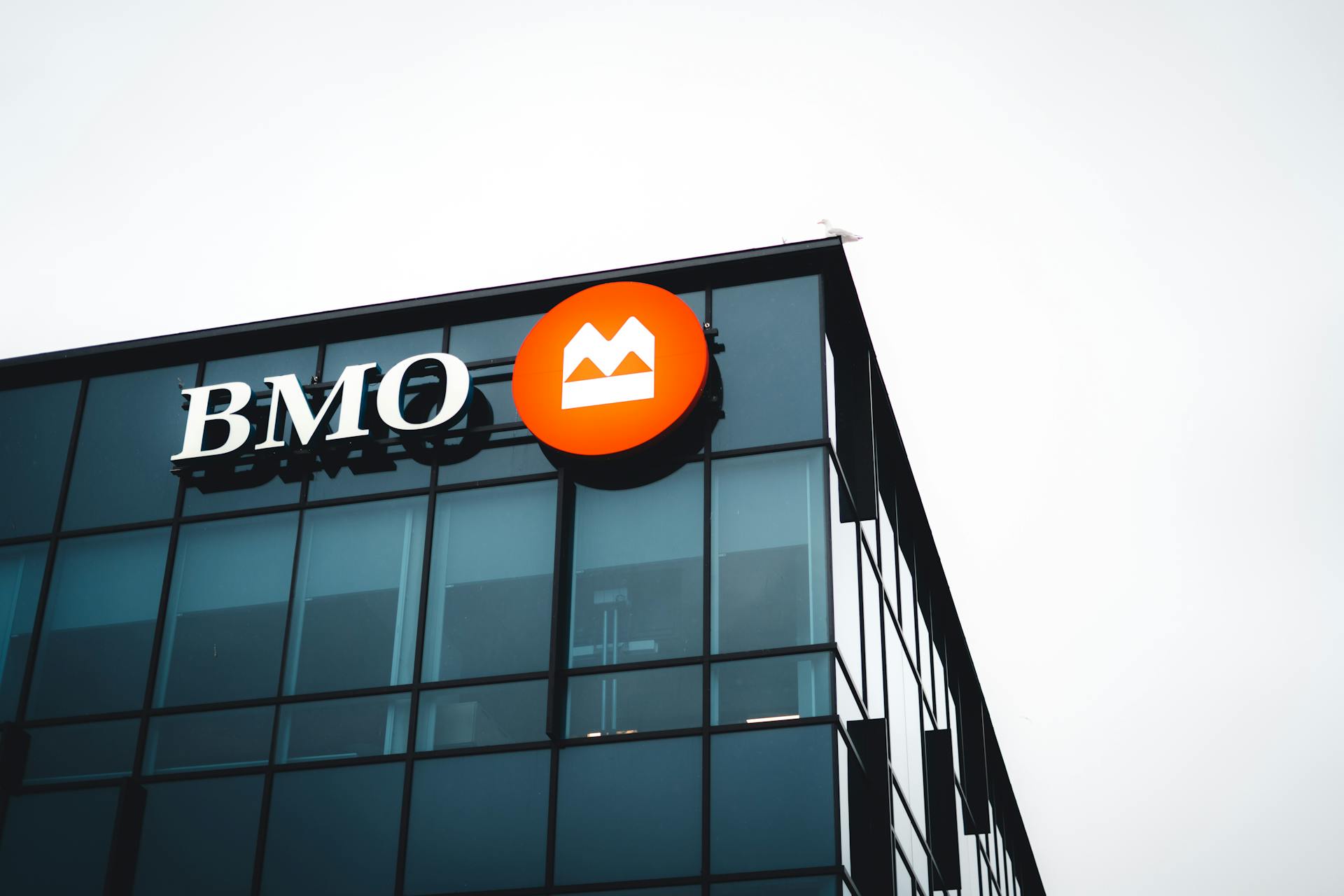 Close-up of a modern building corner featuring a BMO logo on its glass facade.