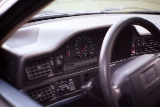 Close-up of a vintage car dashboard and steering wheel, showcasing the speedometer and interior design.
