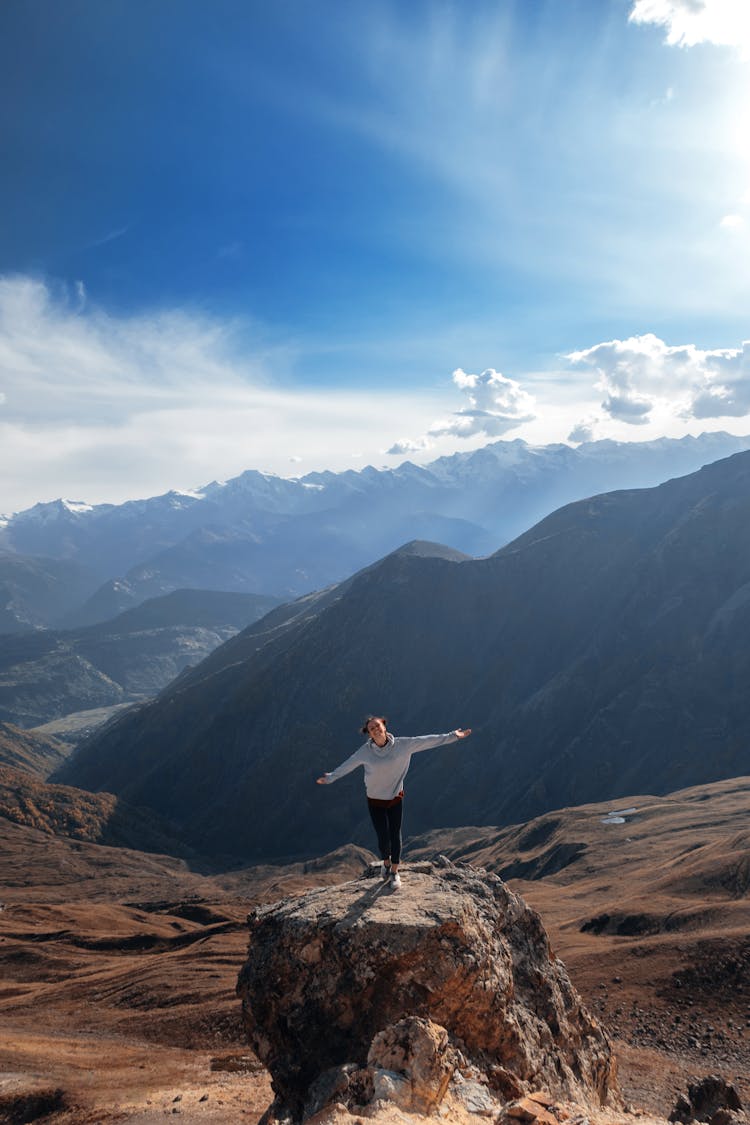 Woman Standing On Rock With Outstretched Arms