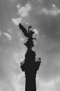 Black and white silhouette of the Angel of Independence against a dramatic sky in Mexico City.