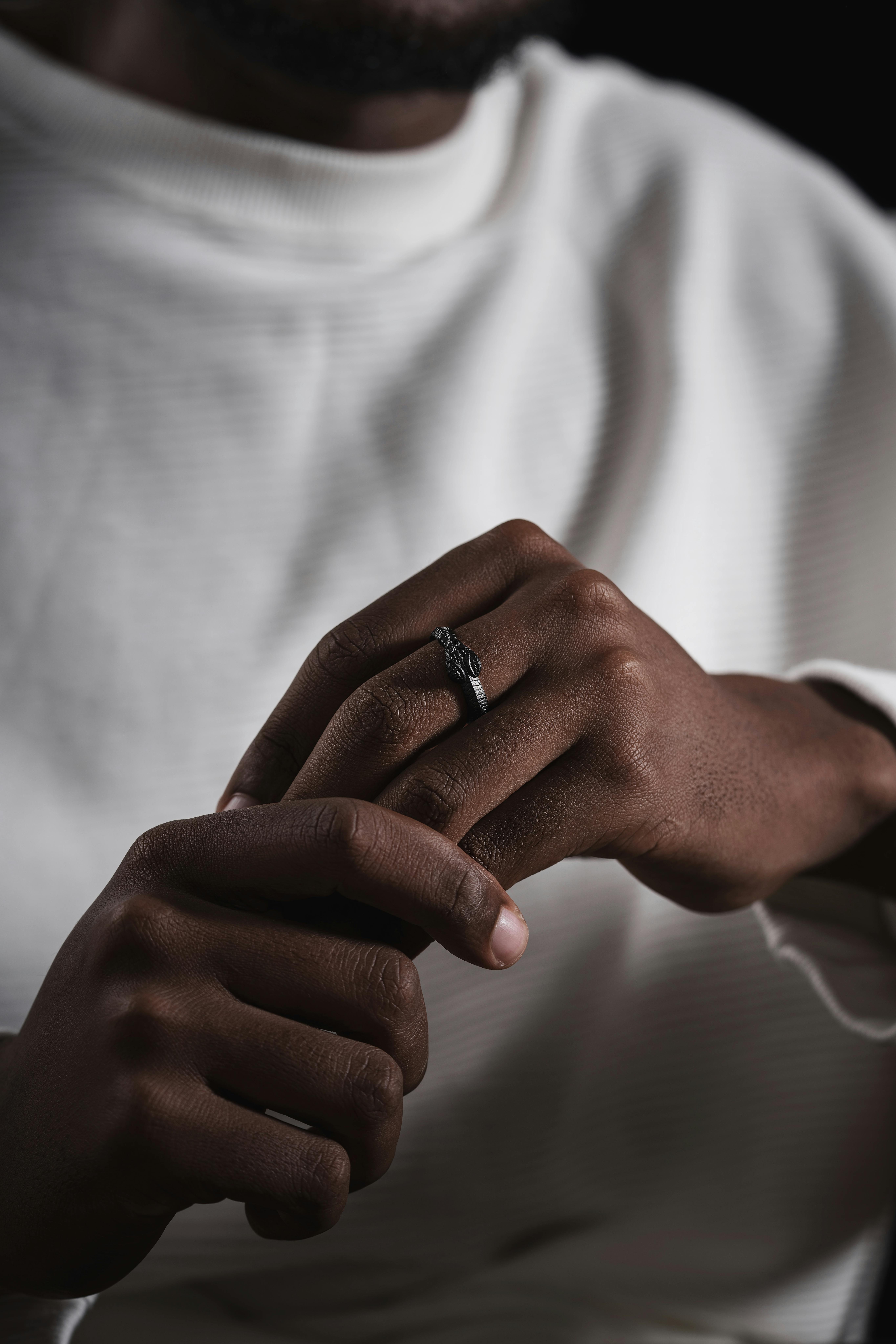 Close-up of a man's hand with a snake ring, emphasizing elegance and style against a dark backdrop.