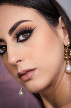 Close-up portrait of a woman with striking makeup and elegant earrings.