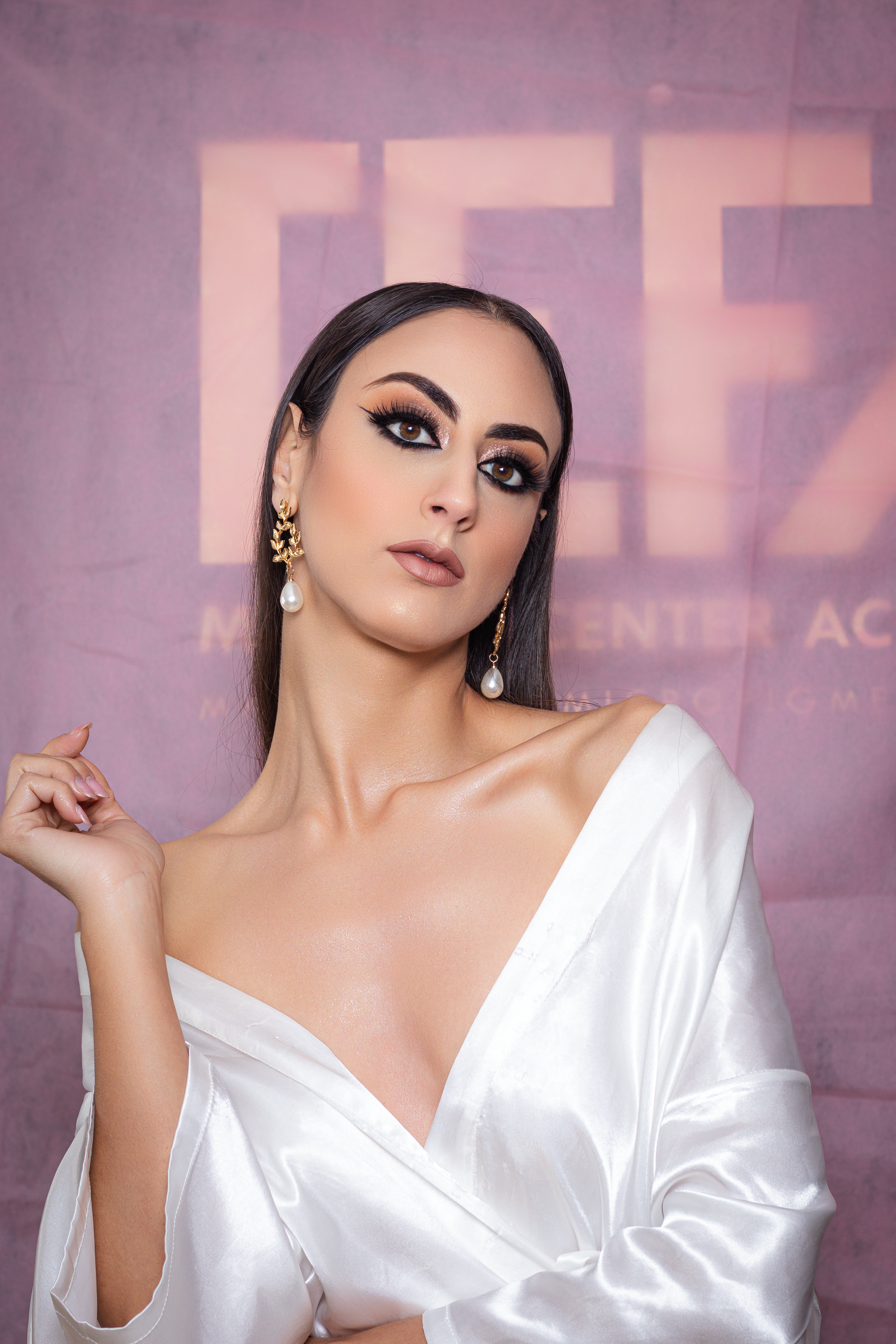 Elegant portrait of a woman in fashion attire against a purple backdrop, showcasing makeup and style.