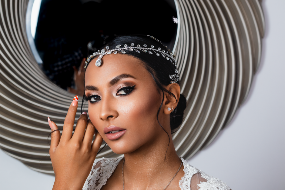 Stunning portrait of a woman wearing elegant jewelry in front of a decorative mirror.