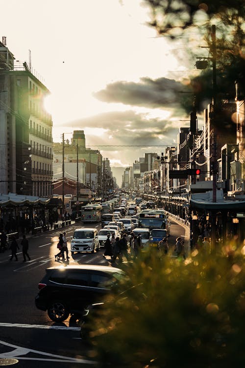 View of a Busy City Street with Sun Shining behind Clouds 