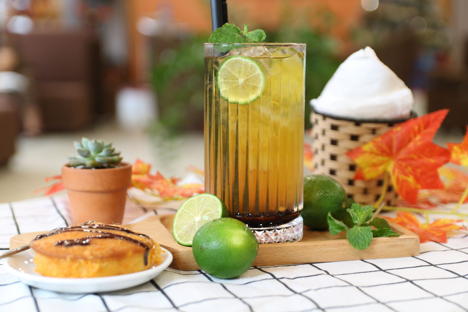 A vibrant lime iced tea garnished with fresh mint, paired with a sweet dessert on a cozy autumn setting.