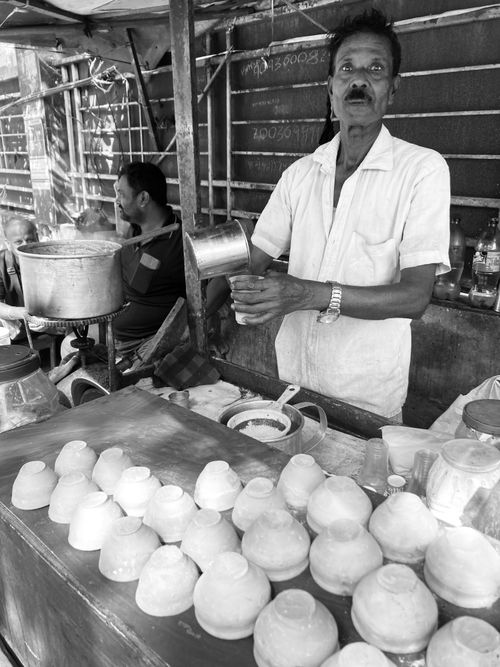 Free A street vendor in Kolkata, India, preparing food surrounded by dishes and cookware. Stock Photo