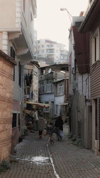 A picturesque narrow alley in Türkiye, blending old and modern architecture with people walking.