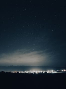 Stunning star-filled sky above a glowing, illuminated city at night.