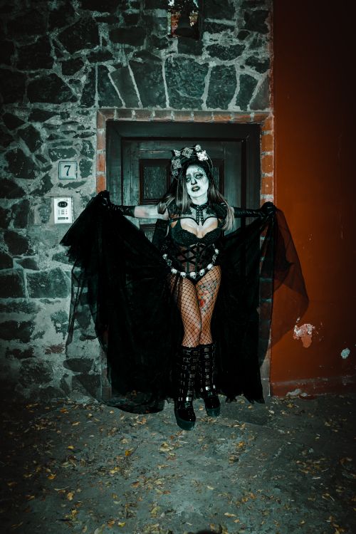 Free A woman in a gothic costume poses in front of a stone wall in Mexico City. Halloween theme. Stock Photo