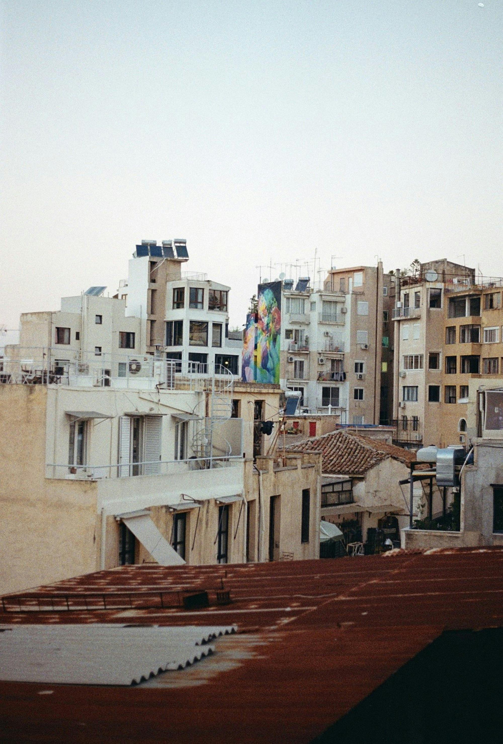 Captivating view of Athens rooftops at sunset featuring a vibrant street art mural.