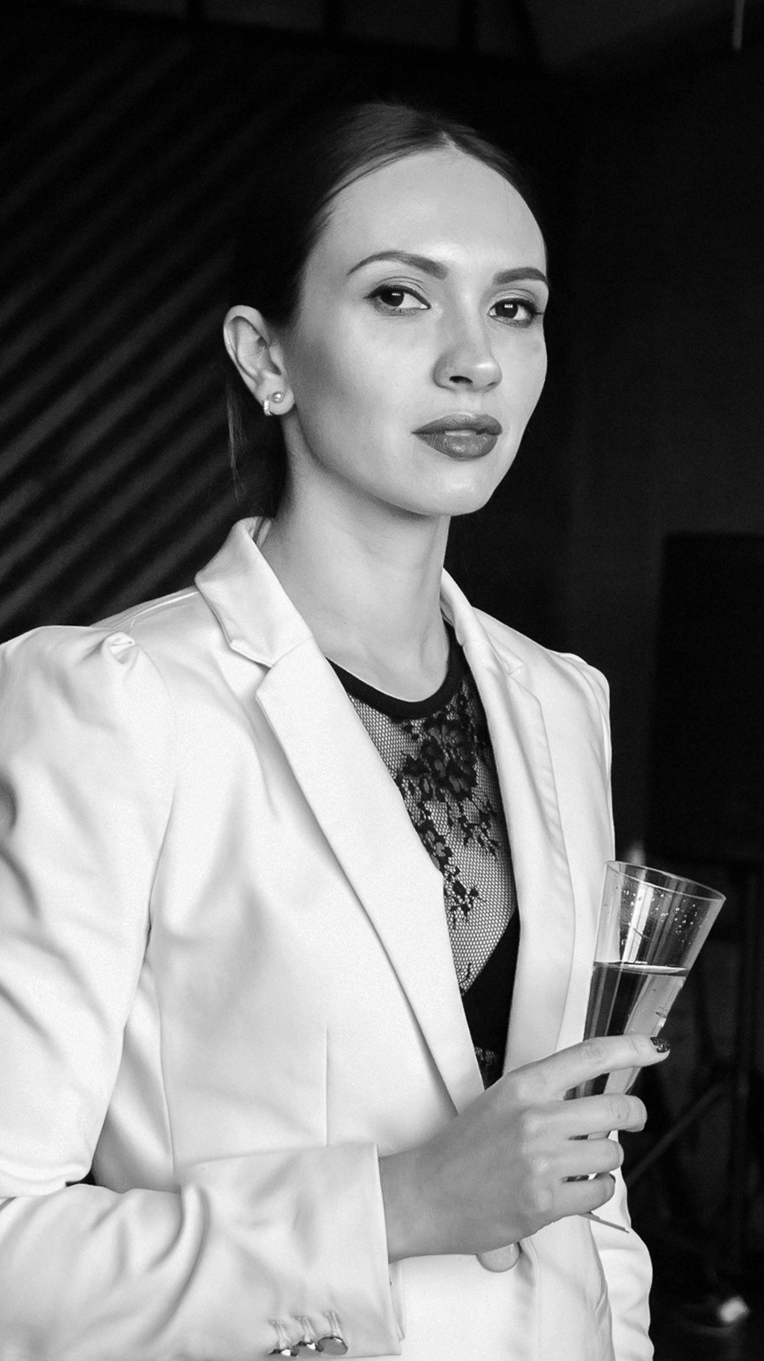 Black and white portrait of a stylish woman holding a champagne glass, exuding elegance and confidence.