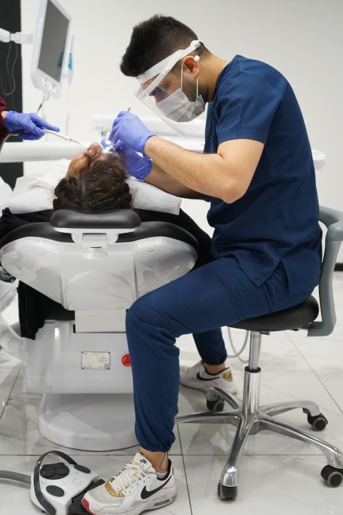Free Dentist wearing protective masks and gloves performing treatment on patient in a modern clinic. Stock Photo